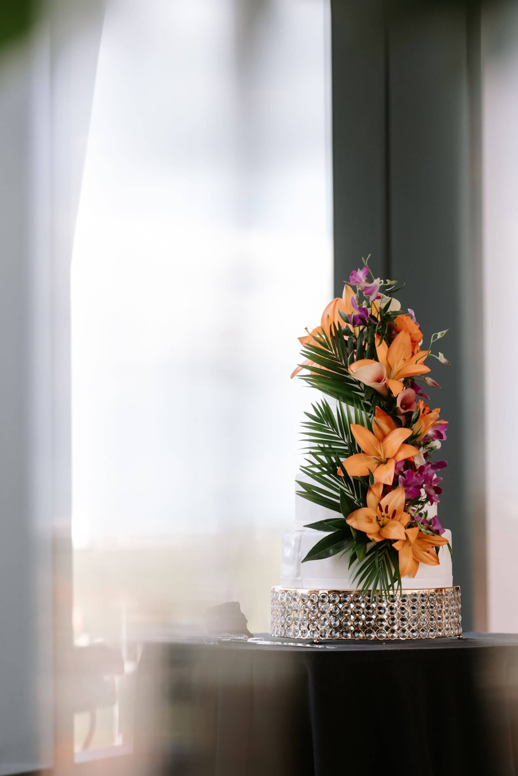 White wedding cake with beautiful tropical flowers on it.